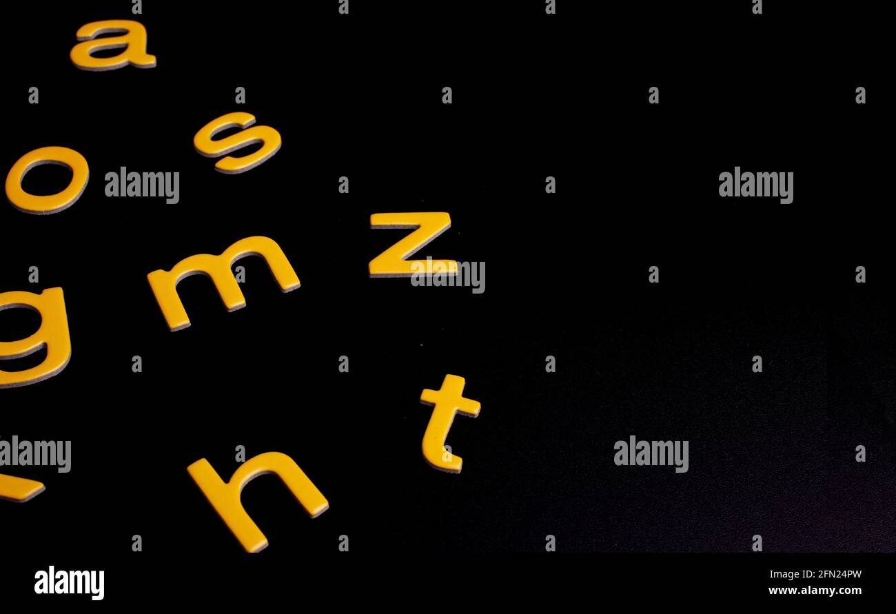 yellow random letters on black background with copy space Stock Photo