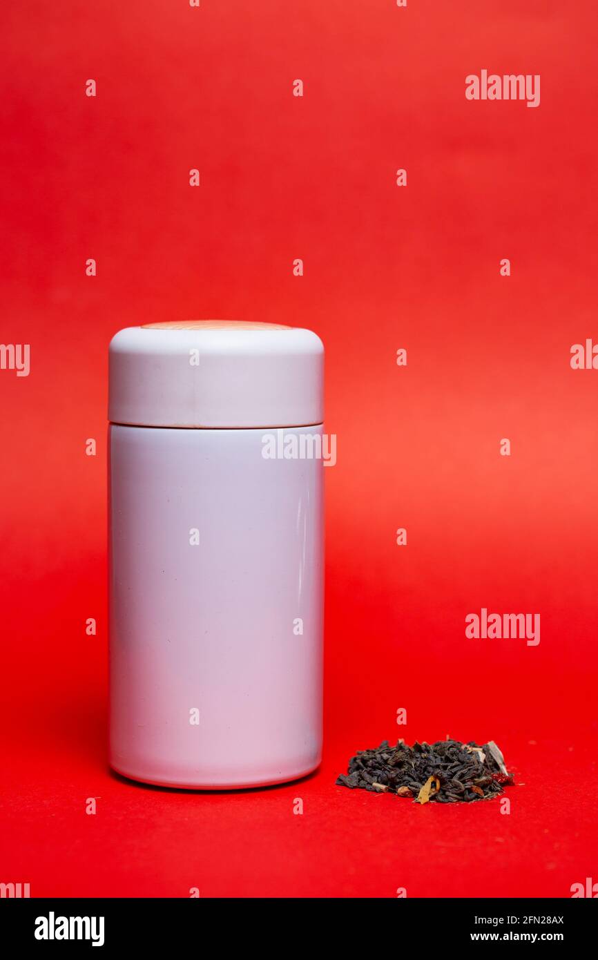 white thermos with green leaf tea on a red background. Stock Photo