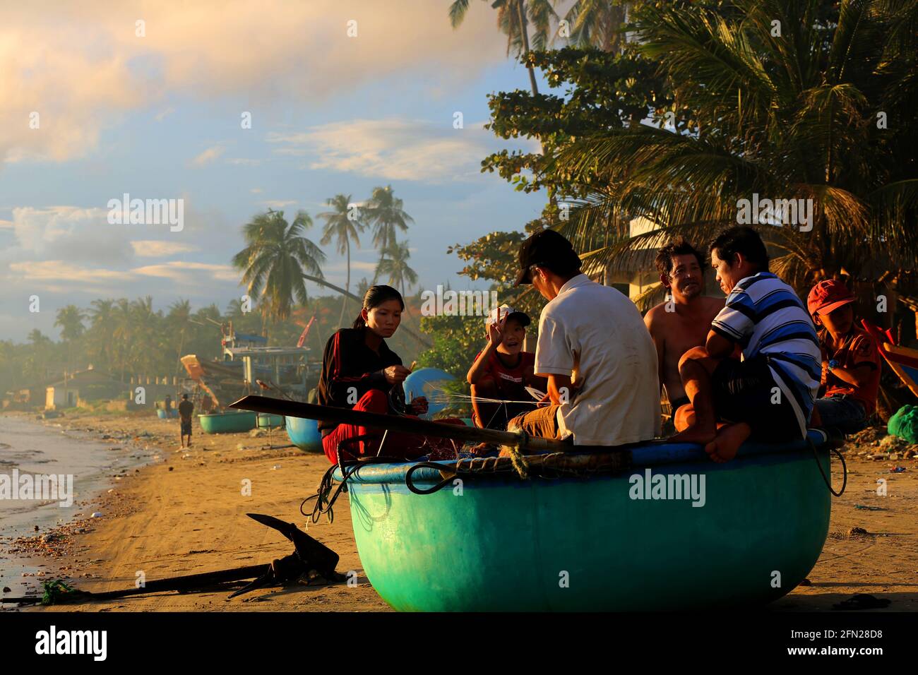 Gruppe von Fischern sitzt in einem Boot unter Palmen um zu Speisen Stock Photo