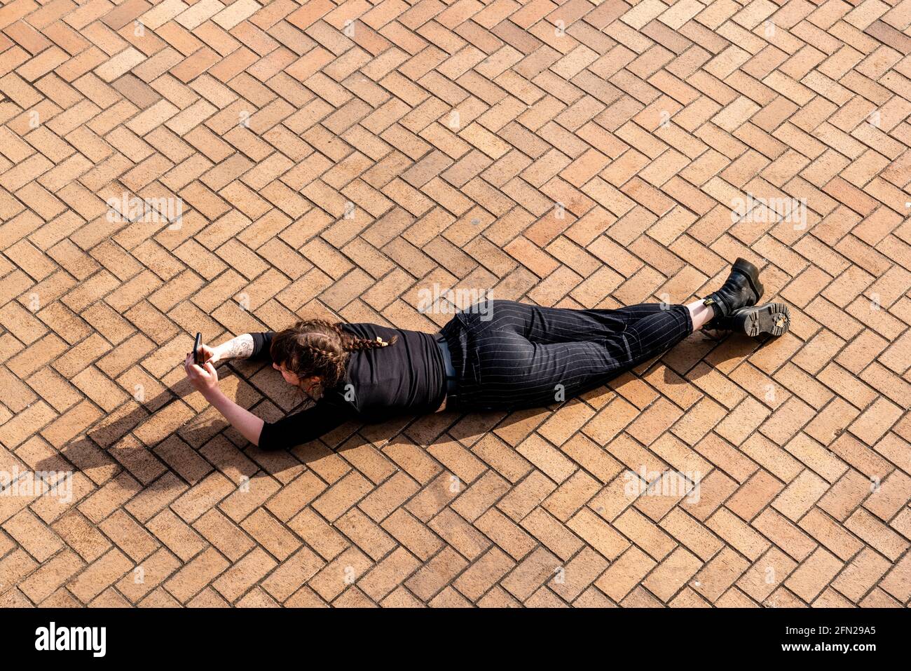 A Young Woman Taking A Photo Whilst Laying Down, Brighton Seafront, Brighton, East Sussex, UK. Stock Photo