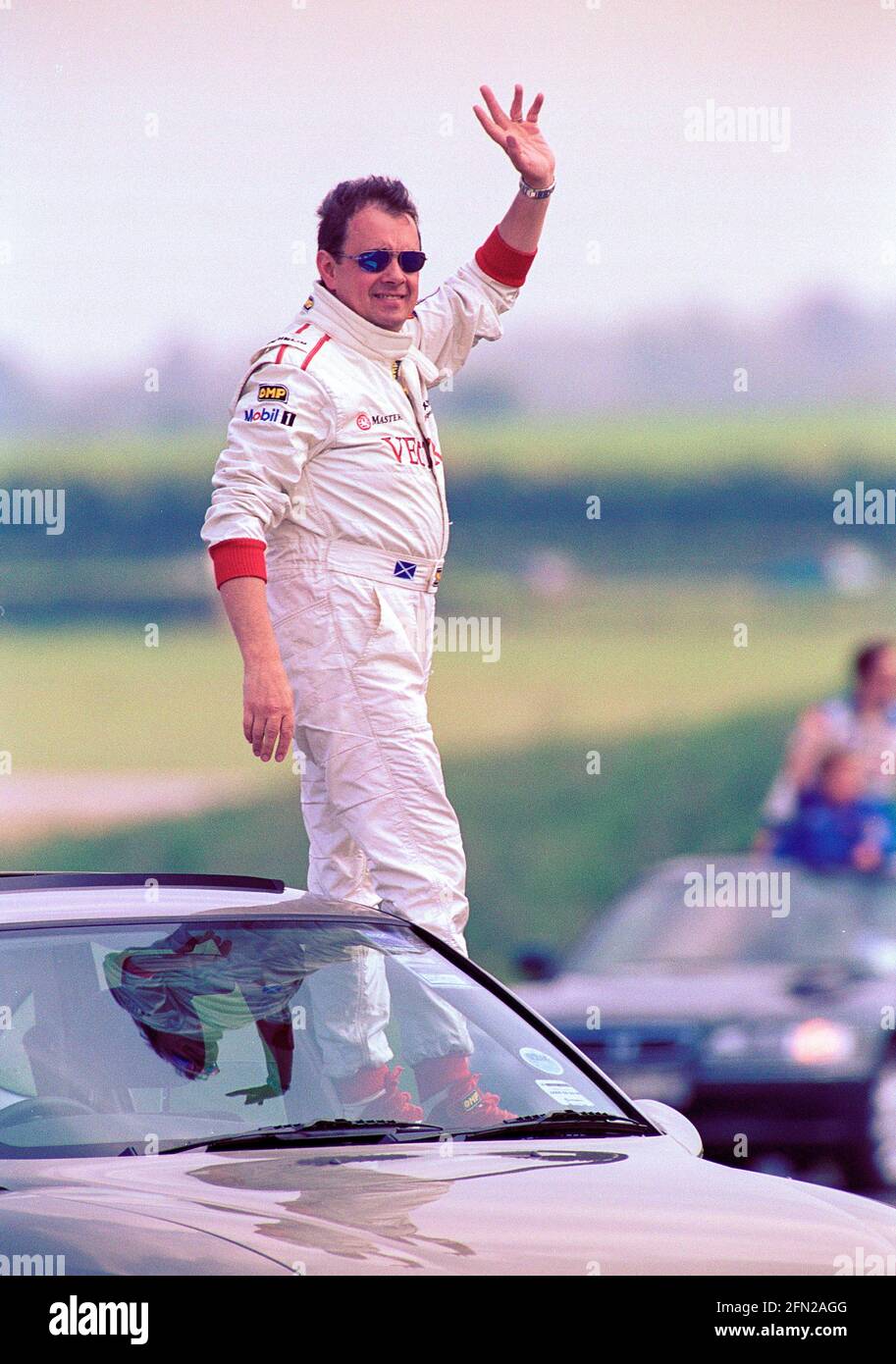 John Cleland stood on car door window on the parade lap waving to the crowd of the 1999 BTCC rounds 5 and 6 at Thruxton Circuit UK. Stock Photo