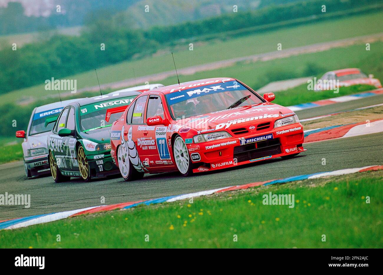 Matt Neal at Thruxton Circuit during the 1999 British Touring Car Championship driving his Max Power Racing Team Dynamics Nissan Primera GT being hotly pursued through club chicane. Stock Photo