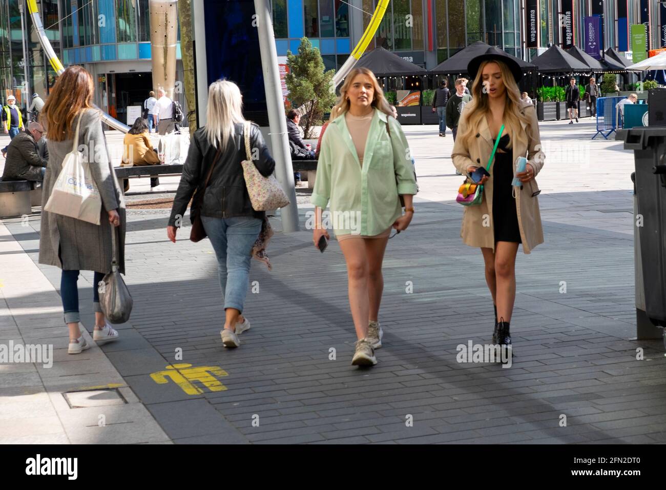 Young women female friends walking in Cardiff City Centre pedestrianised street outside Central Library lockdown restrictions eased Wales UK in 2021 Stock Photo