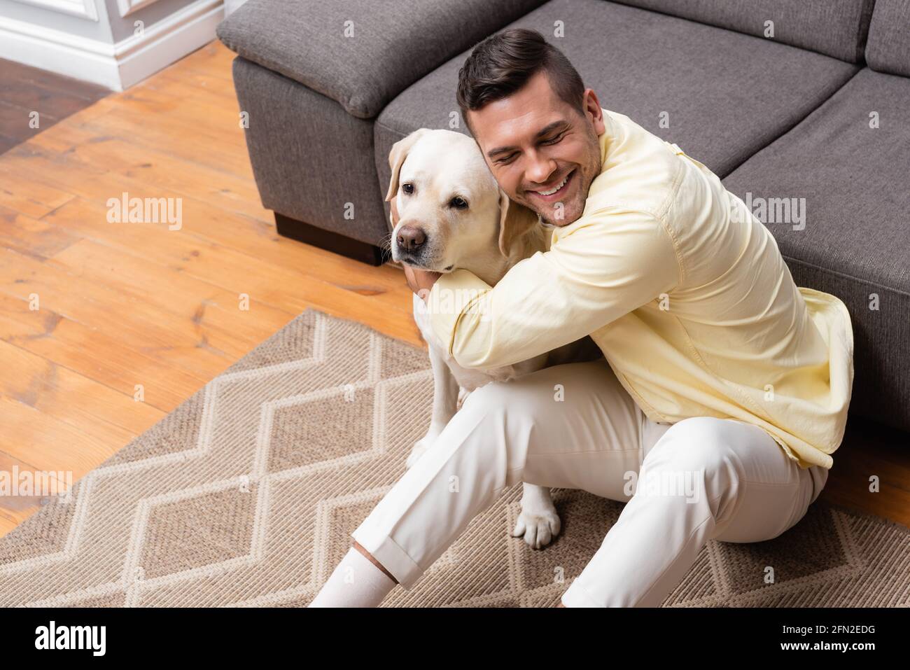 high angle view of man with closed eyes sitting on floor and hugging ...