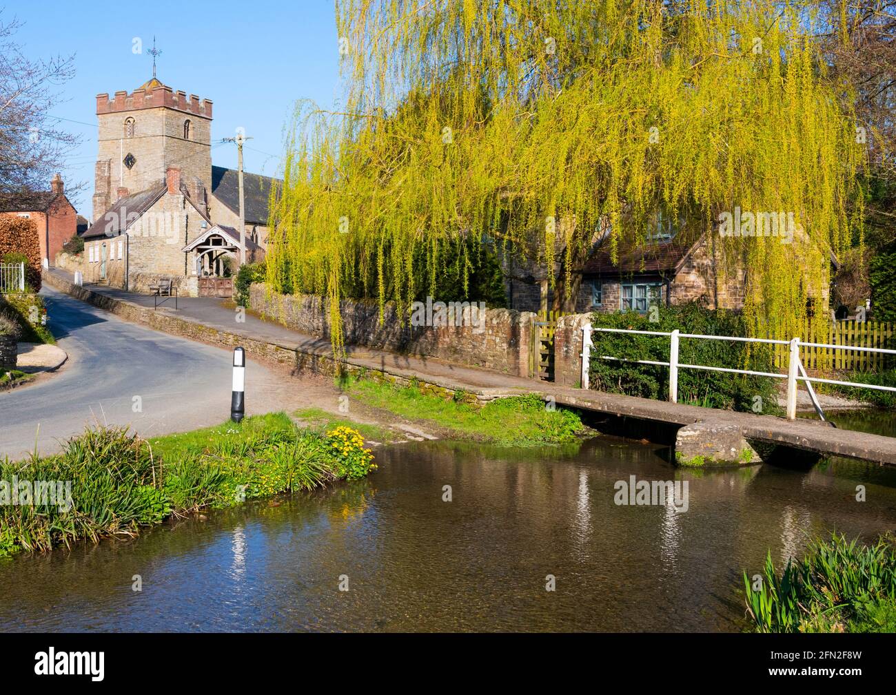 The village of Diddlebury with St Peter's Church and a tributary of the River Corve, Shropshire. Stock Photo