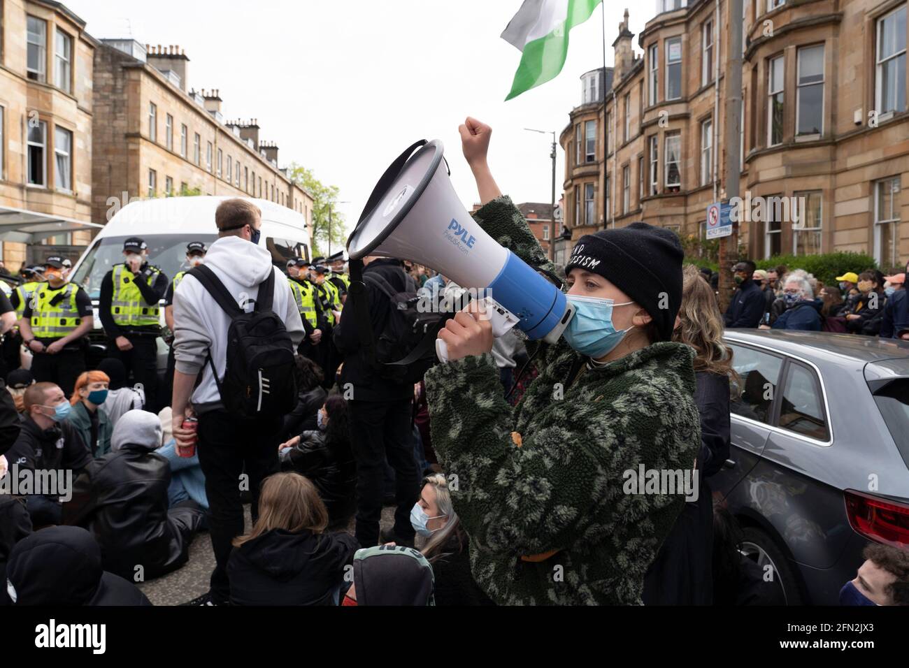 Glasgow, Scotland, UK. 13th May, 2021. Protesters gather in Pollokshields to prevent the deportation of individual from household. Heavy police presence continues with a tense stand-off between the police and protesters who are sitting in Kenmure Street Street blocking access. Credit: Iain Masterton/Alamy Live News Stock Photo