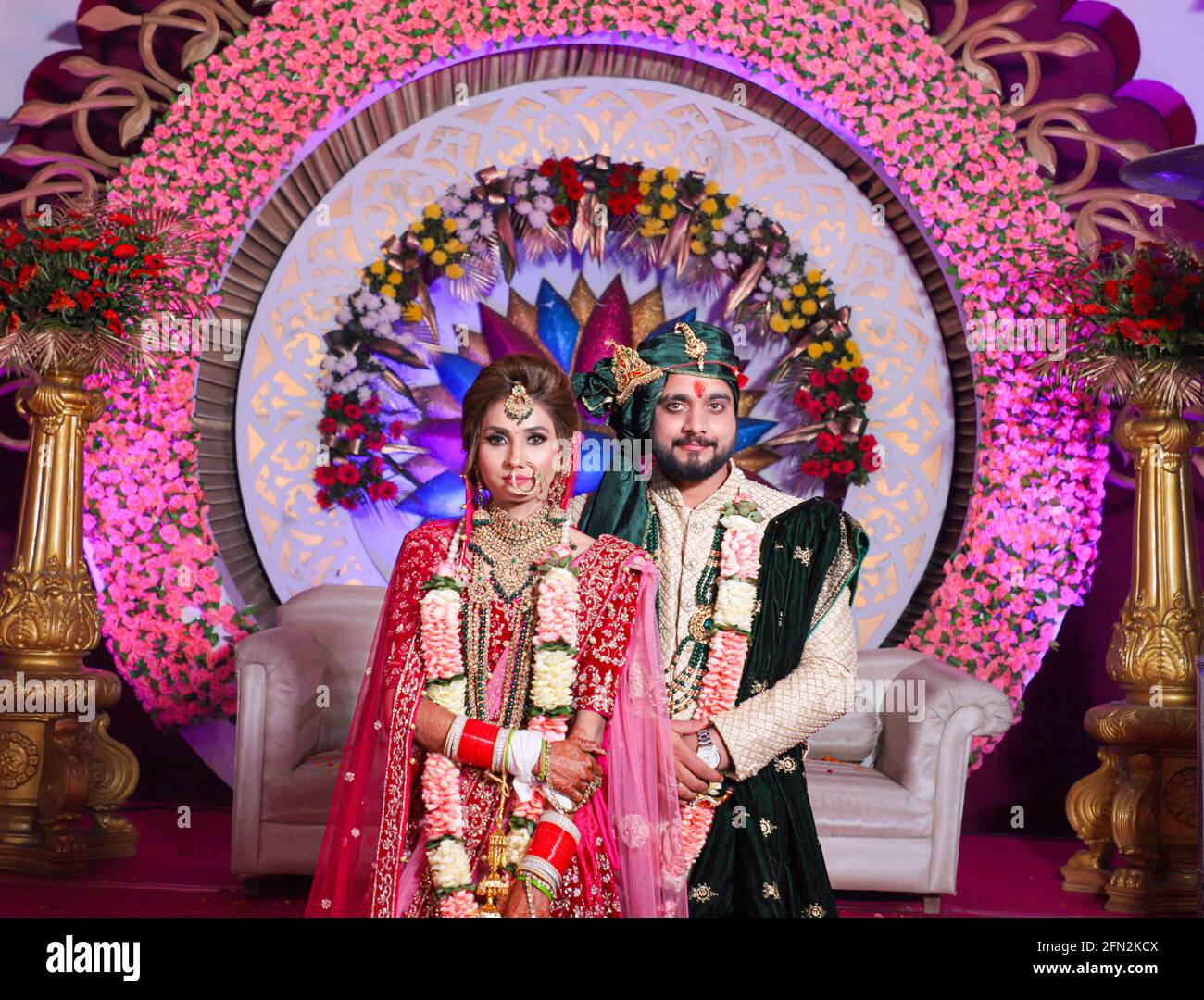 gorgeous stunning indian bride and groom wearing traditionally dress are posing on their wedding ceremony 2FN2KCX