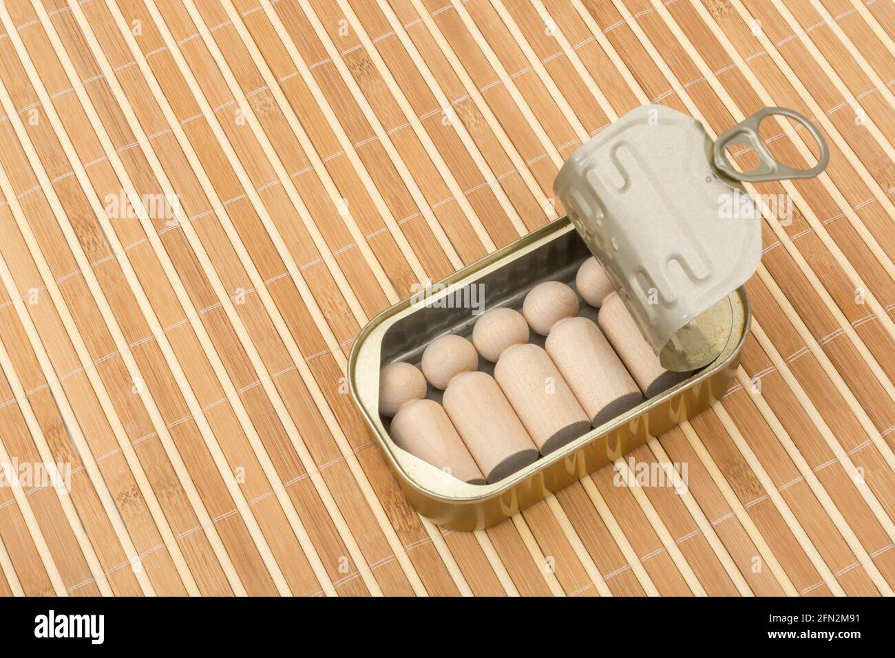 Tinned fish can with small wood figures representing humans. For packed in like sardines, no room to move, tight fit, squashed together, overcrowded. Stock Photo