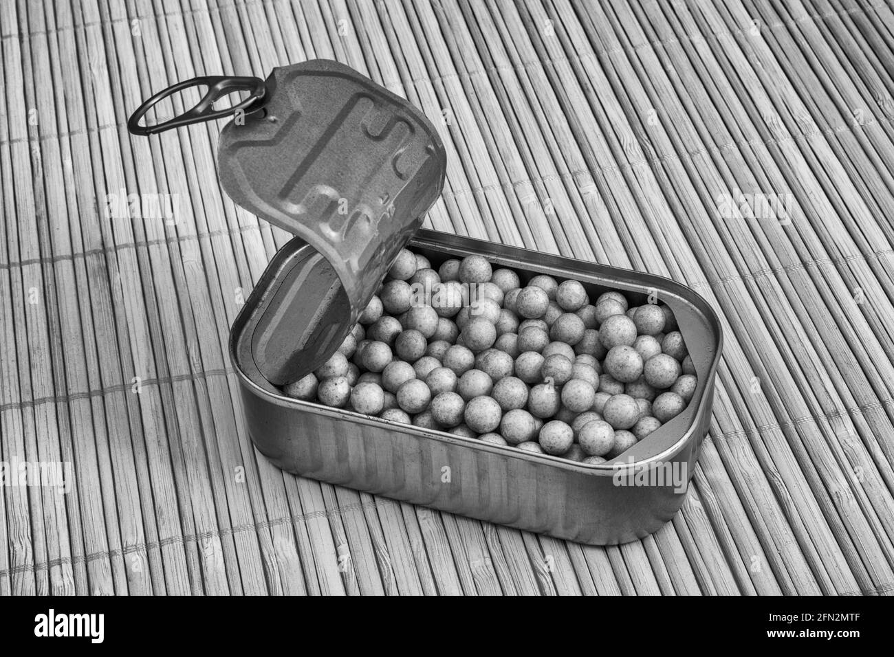 Black and white of fish can with small styrene spheres. For packed in like sardines, no room to move, tight fit, squashed together, overcrowded. Stock Photo