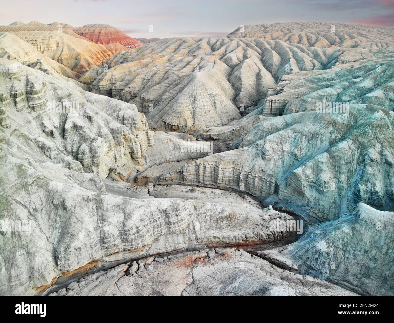 Aerial drone Landscape of Bizarre layered red, blue and white desert mountains with canyon in beautiful national park Altyn Emel in Kazakahstan Stock Photo