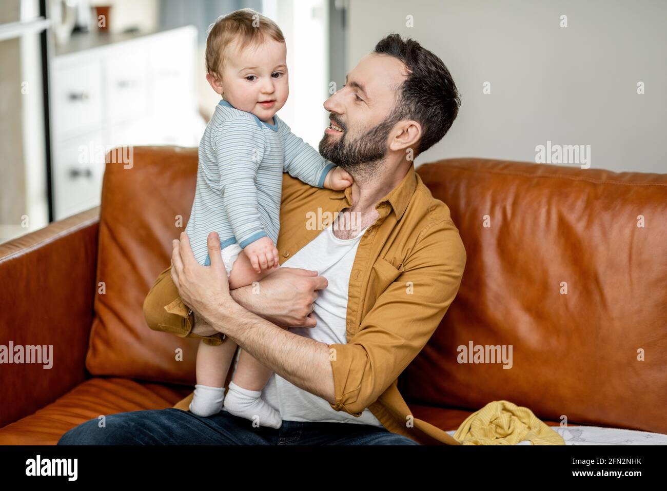 Happy middle aged dad carrying and playing with newborn baby alone ...