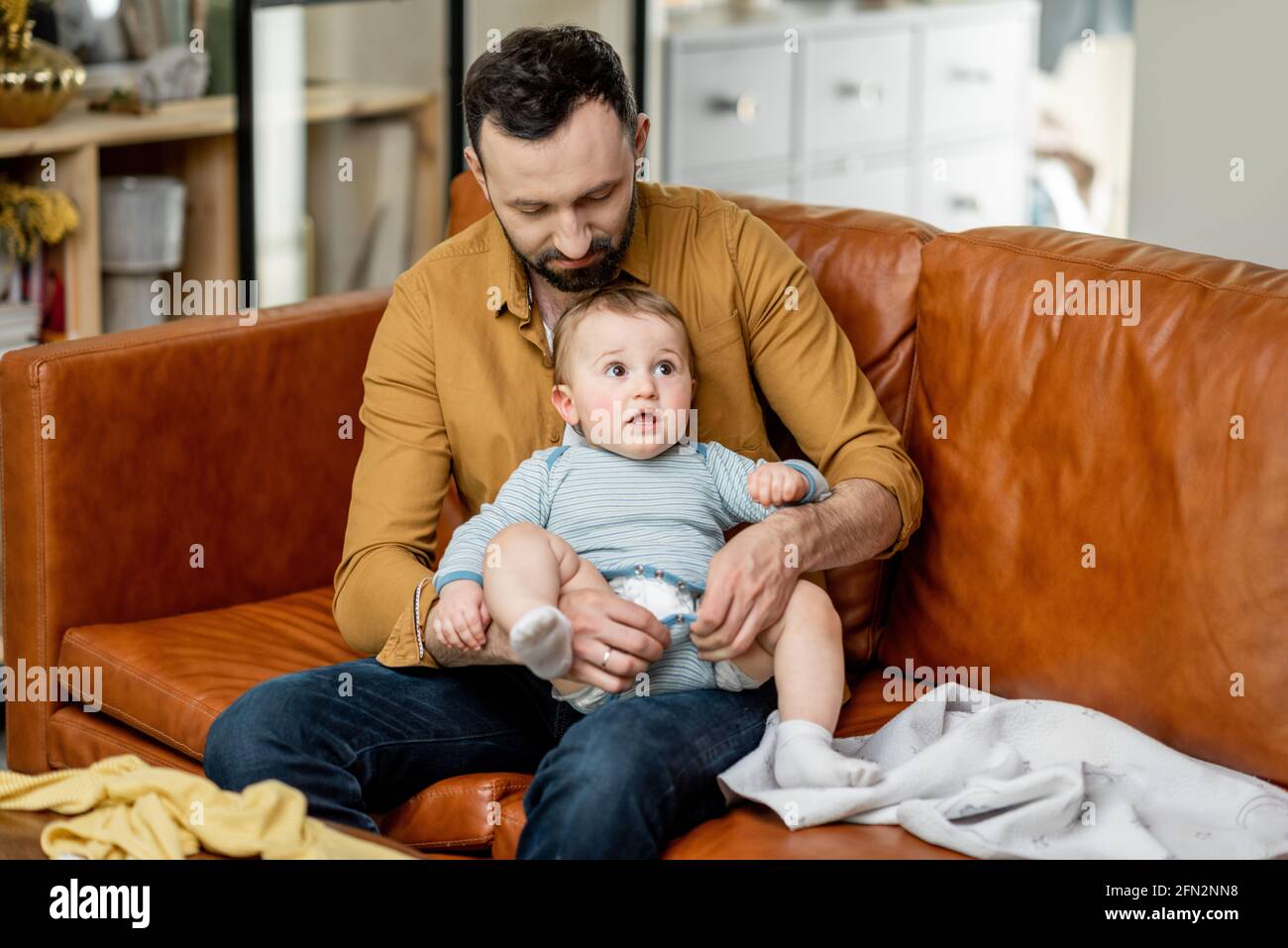 Father changing diaper to his baby son alone at home. Babysitter dad