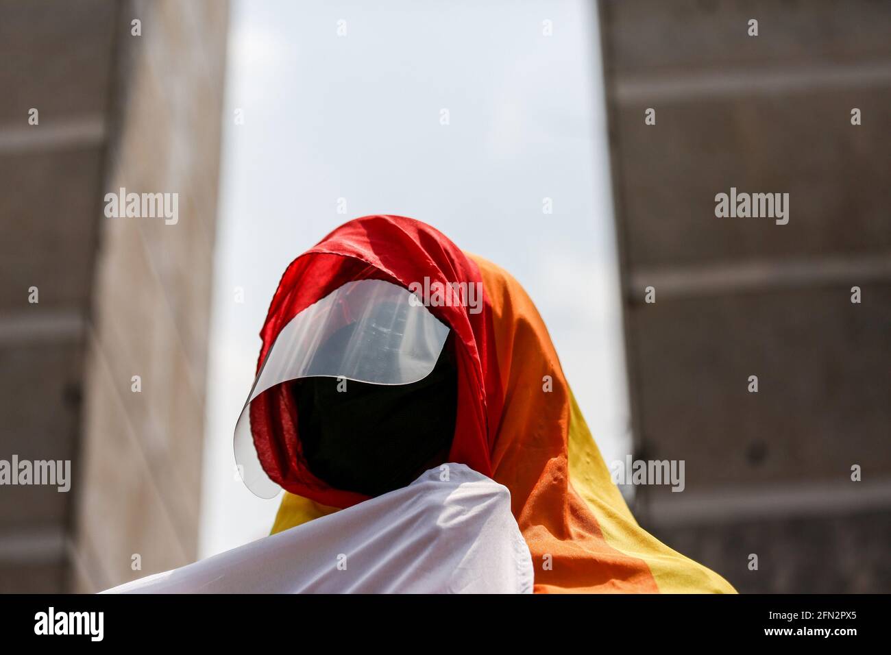 An activist wears a rainbow flag as thousands of activists join a protest in celebration of Labor Day in Quezon City. Various groups called for adequate labor rights and benefits such as minimum wage increase, financial assistance and mass testing due to COVID-19. Metro Manila, Philippines. Stock Photo