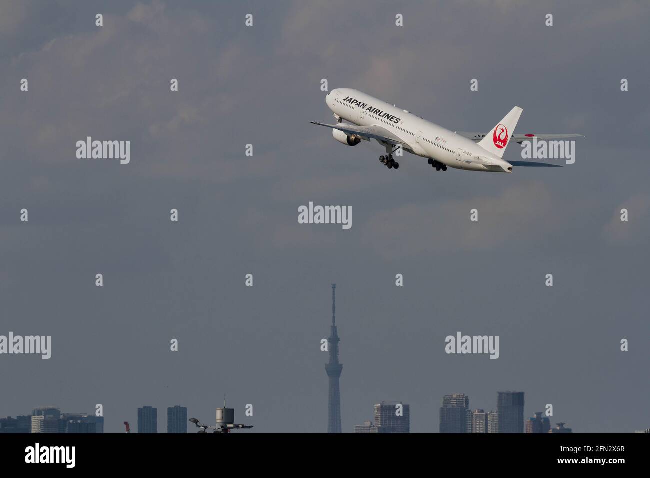 A Boeing 777-289 operated by Japan Airlines (JAL) takes off from Haneda Airport and flies over Tokyo Skytree. Stock Photo