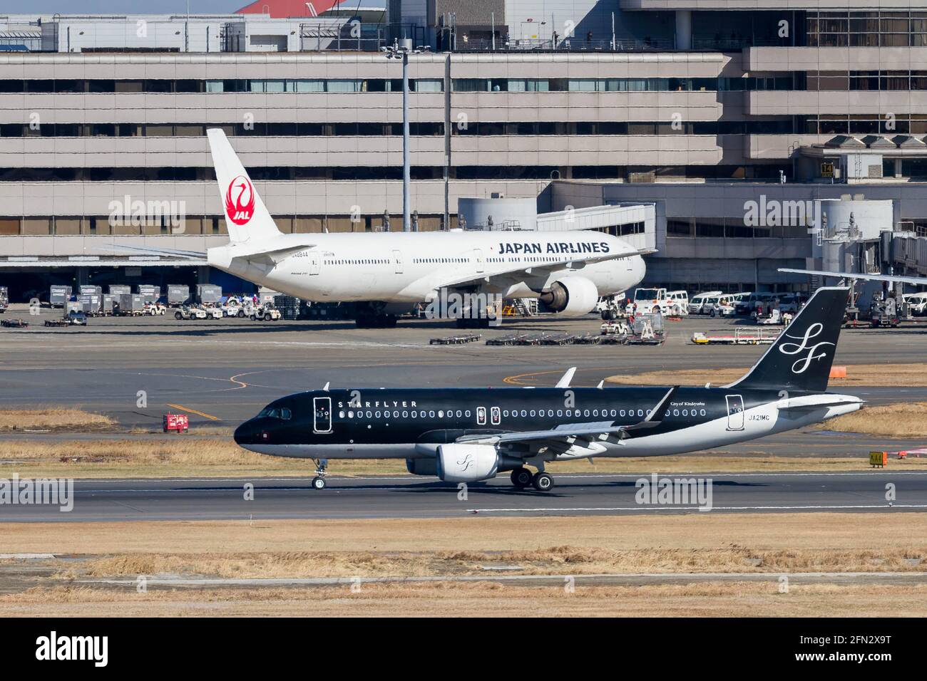 Airbus A320-214 airliner with Starflyer airlines passes in front of a JAL Boeing 777 at Haneda International Airport. Stock Photo