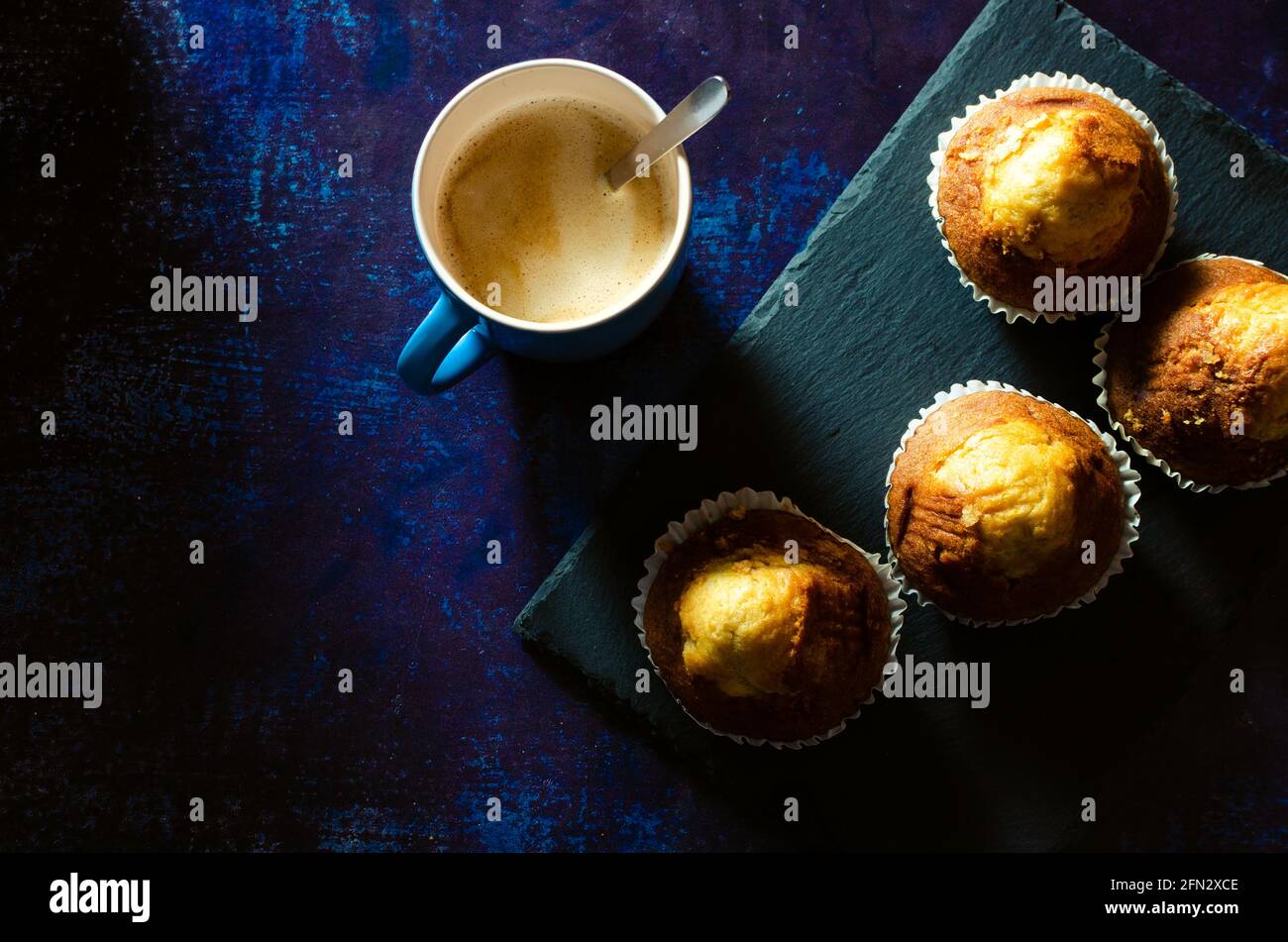 Breakfast of coffee with muffins on a slate plate on a rusty blue background. Dark food Stock Photo