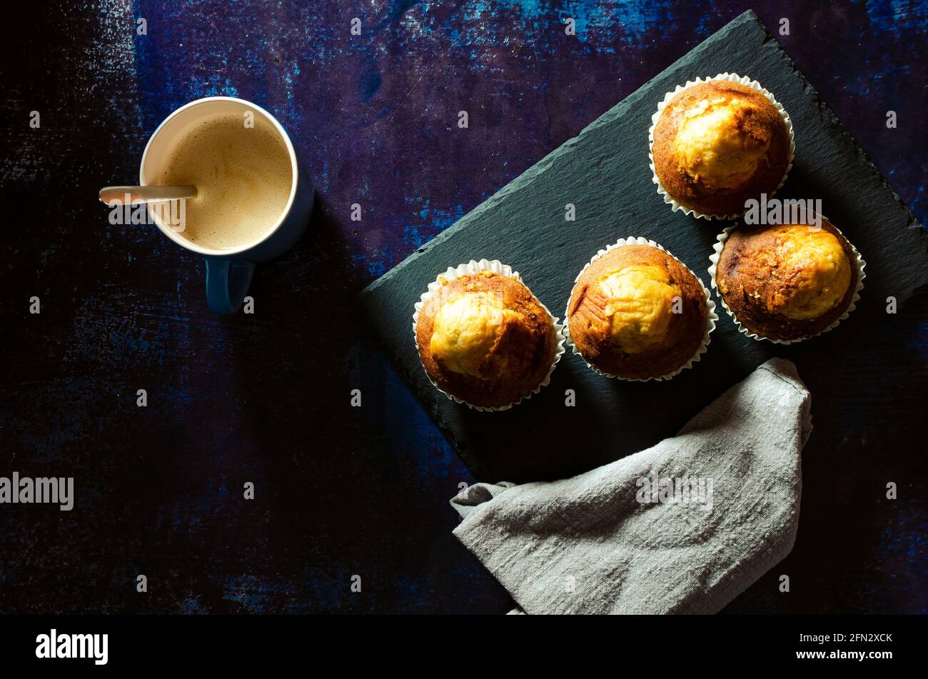 Breakfast of coffee with muffins on a slate plate on a rusty blue background. Dark food Stock Photo