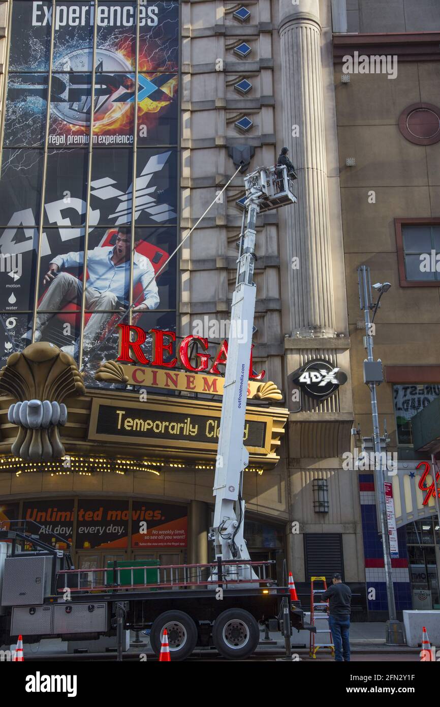 Building maintenance worker up in a cherry picker working on the Regal Theater on 42nd Street at 8th Avenue on the West Side of Manhattan, Times Square neighborhood. Stock Photo