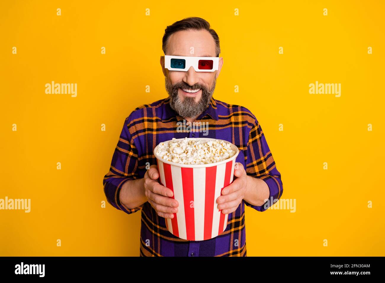 Portrait of attractive cheerful guy holding in hands eating snack corn ...