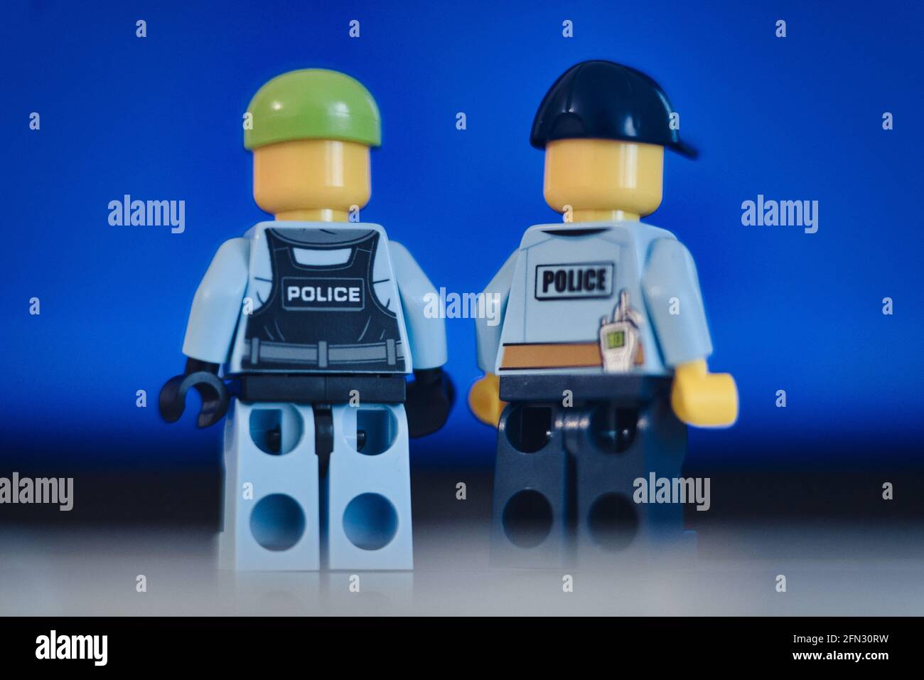 MUNICH, GERMANY - May 13, 2021: Lego figure of a police officer standing in front of blue background. Police and justice system concept Stock Photo