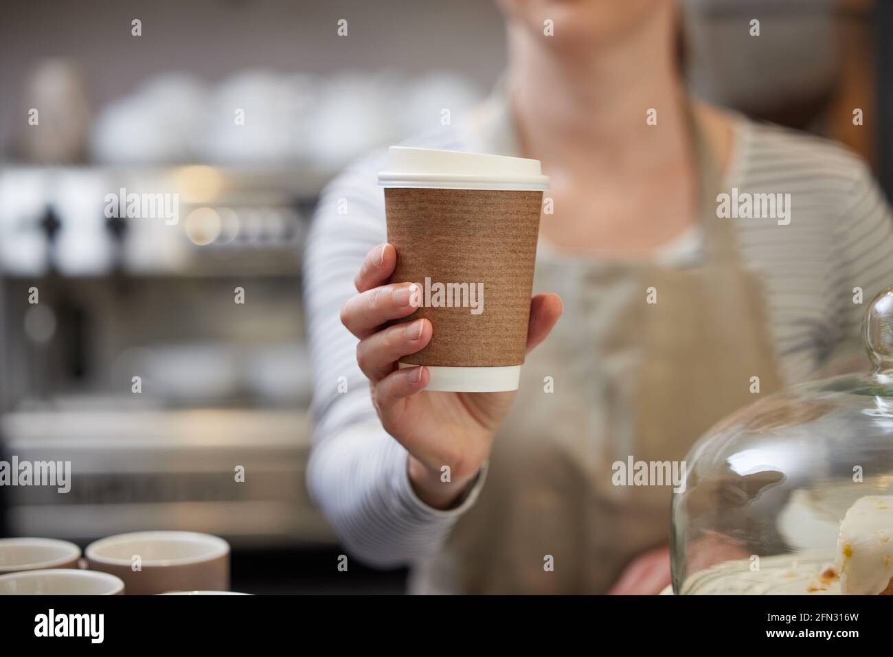 Close Up Of Female Worker in Cafe Serving Coffee In Sustainable Recyclable Cup Stock Photo