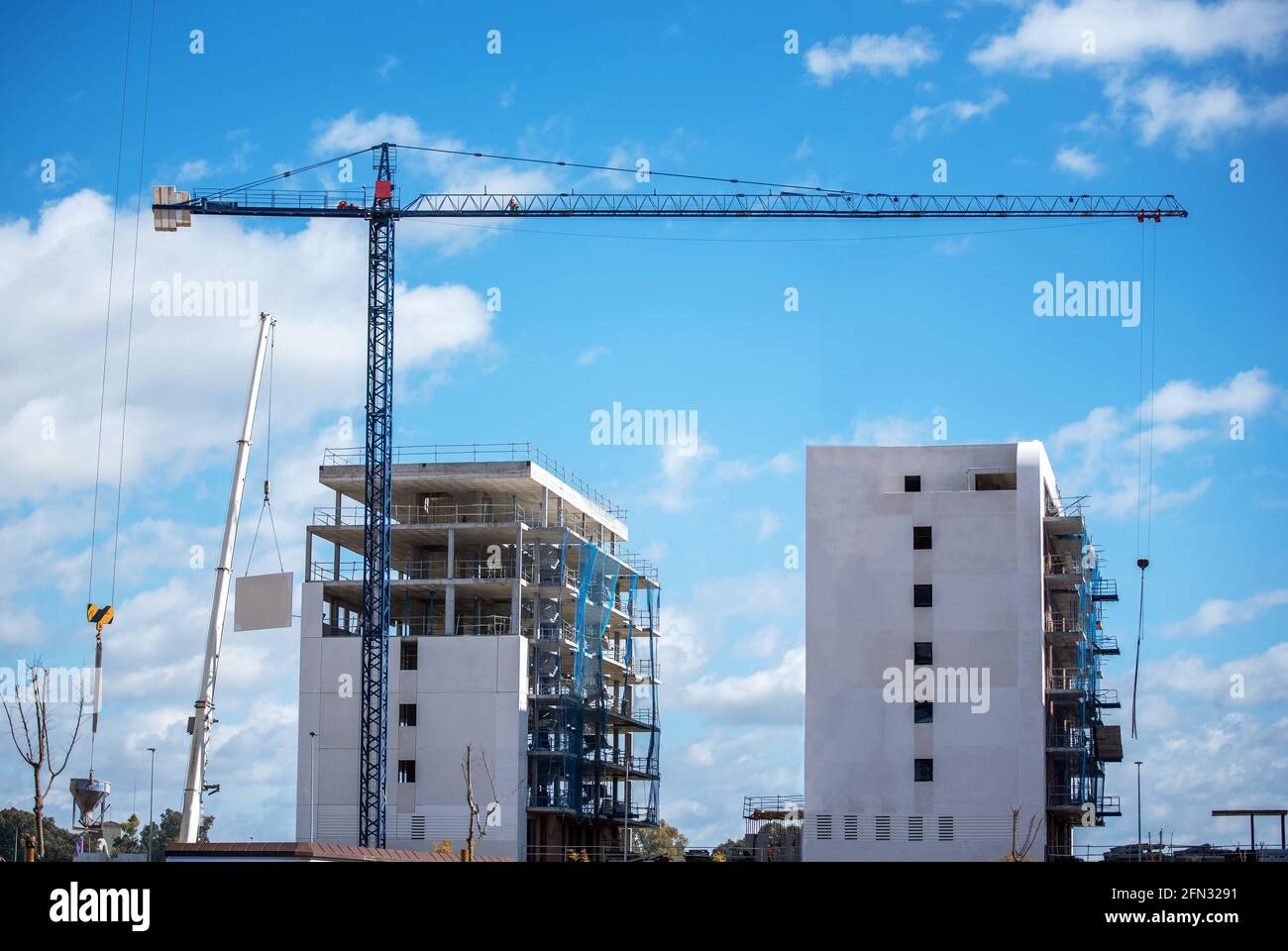 Building under construction with a crane and a blue sky and white clouds. Stock Photo