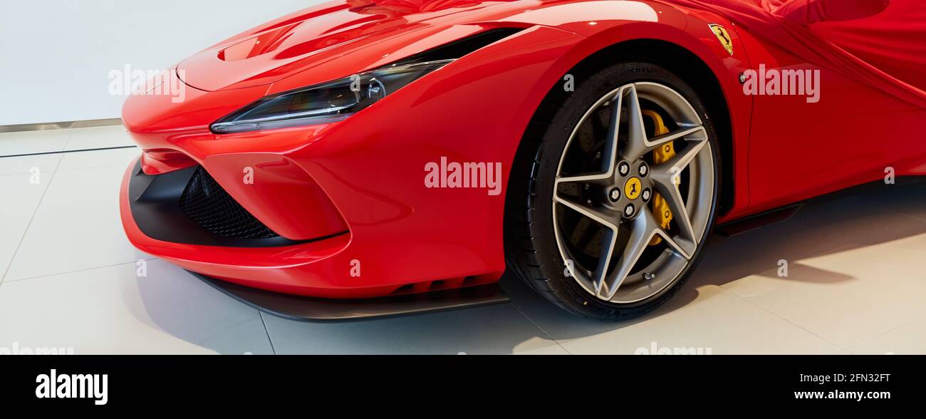 Warsaw/Poland - 04.17.2020:  Front of the latest red Ferrari F8 Tributo partly covered with a cover. The moment the cover is removed when the buyer pi Stock Photo