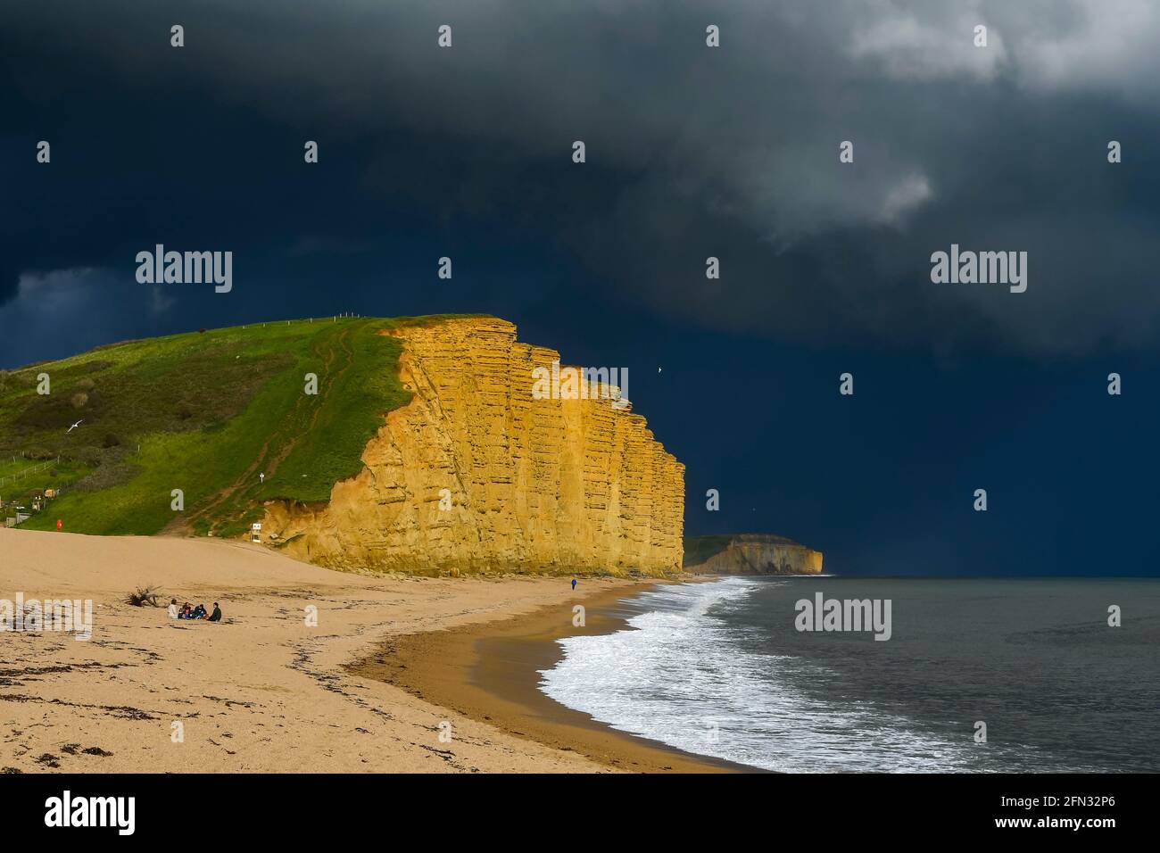 West Bay, Dorset, UK. 13th May, 2021. UK Weather. Dark threatening stormy skies above the cliff and beach at the seaside resort of West Bay in Dorset on an afternoon of sunny spells and heavy showers. Picture Credit: Graham Hunt/Alamy Live News Stock Photo