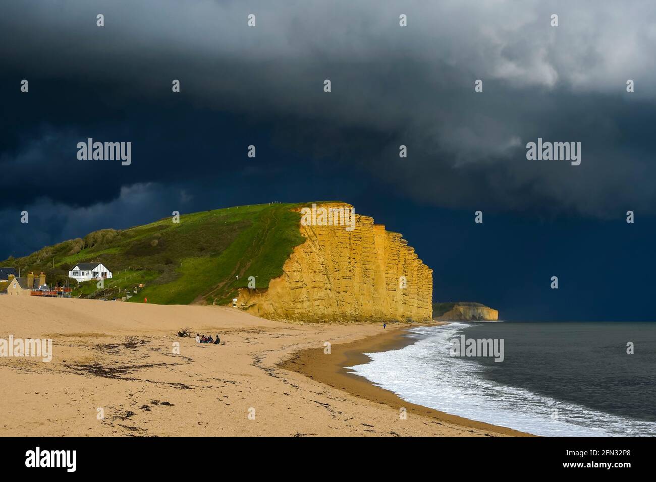 West Bay, Dorset, UK. 13th May, 2021. UK Weather. Dark threatening stormy skies above the cliff and beach at the seaside resort of West Bay in Dorset on an afternoon of sunny spells and heavy showers. Picture Credit: Graham Hunt/Alamy Live News Stock Photo