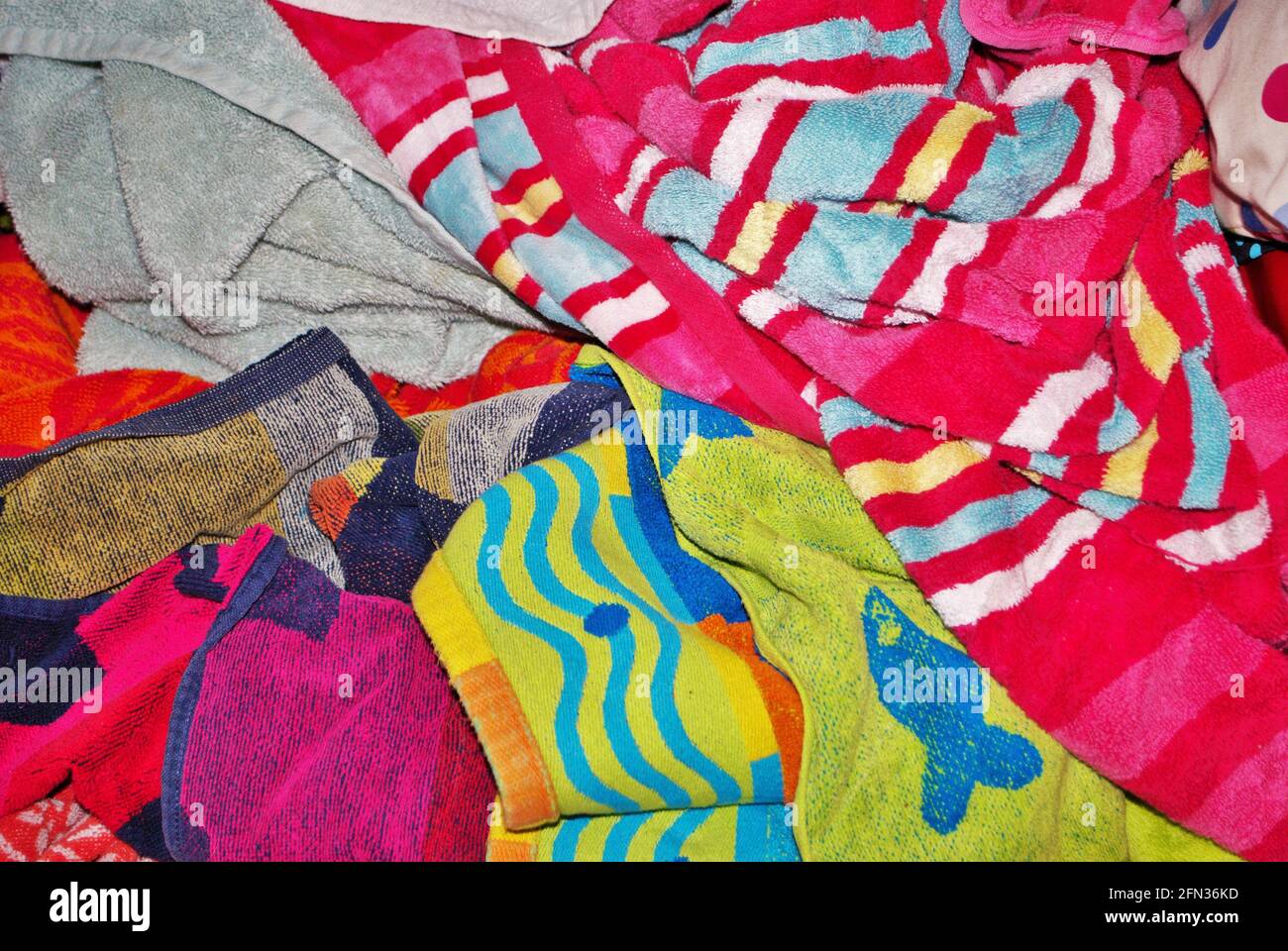 Pile of dirty towels that need to be washed in a basement laundry room