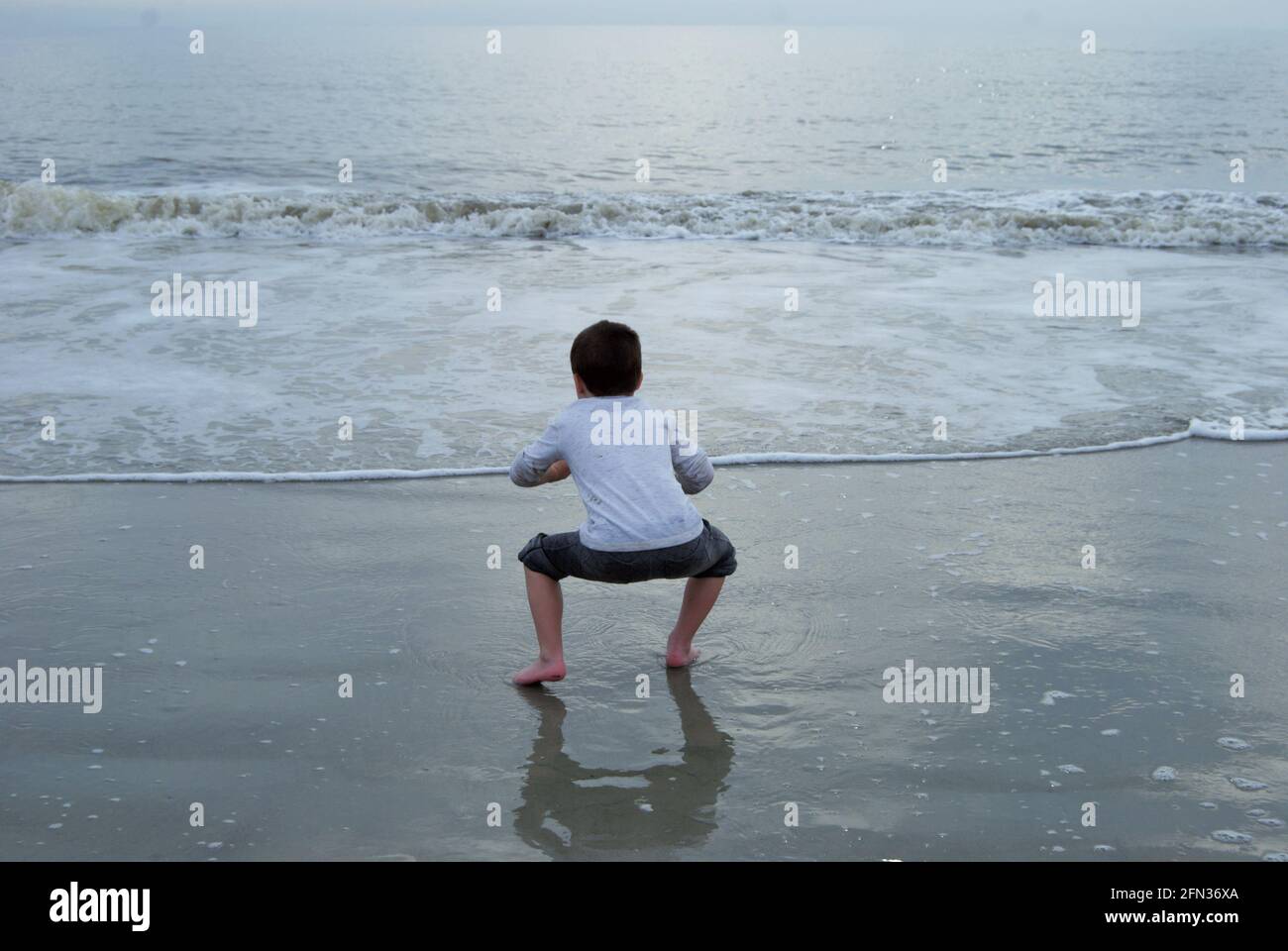 unrecognizable little boy happily dancing and stomping on Daytona beach Florida Stock Photo