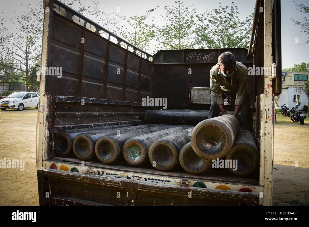 Workers loading and unloading medical oxygen cylinders at a care centre ...
