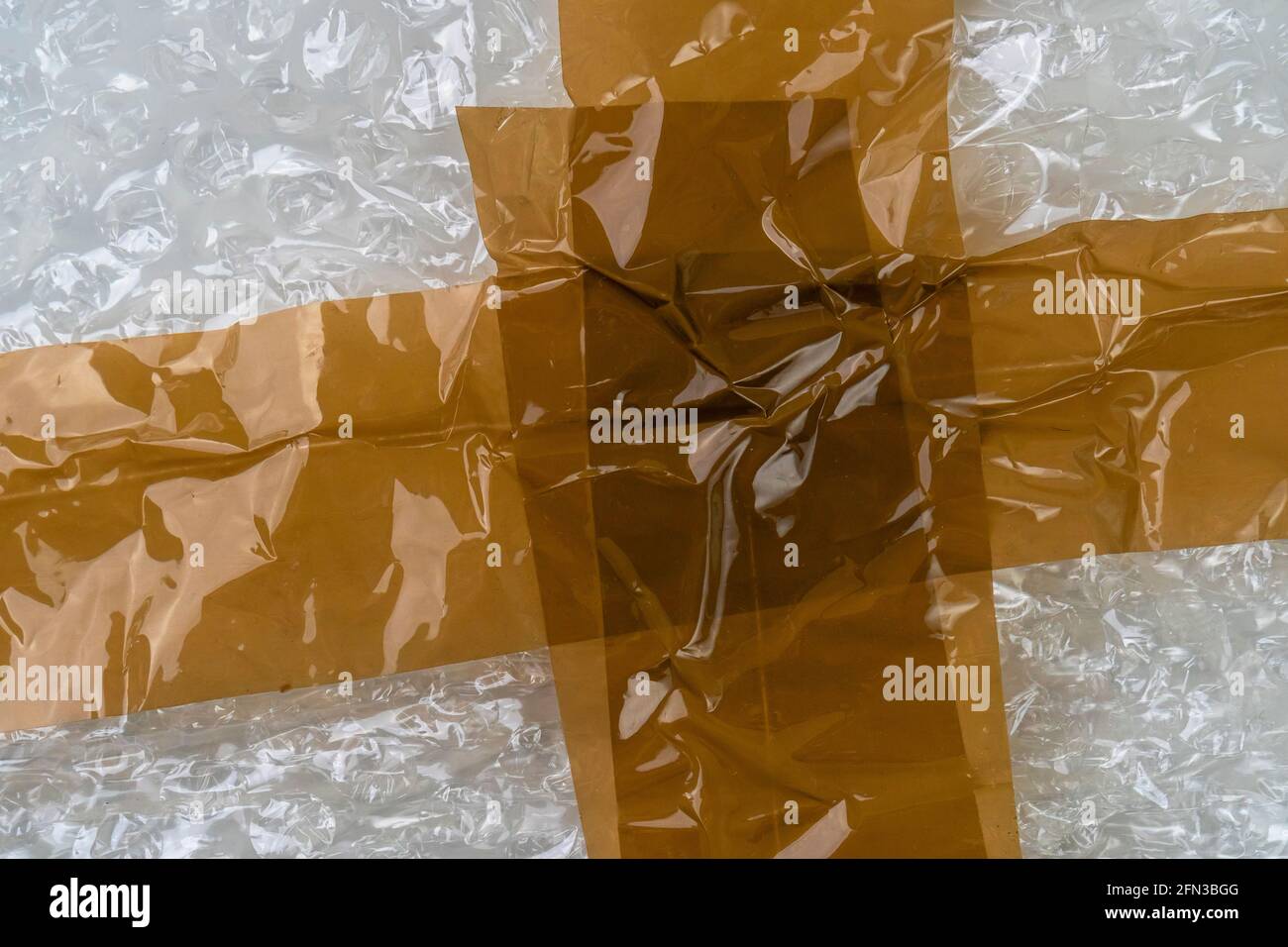 Adhesive tape on a bubble wrap. Wrinkled Abstract plastic background. Delivery concept. Macro Stock Photo