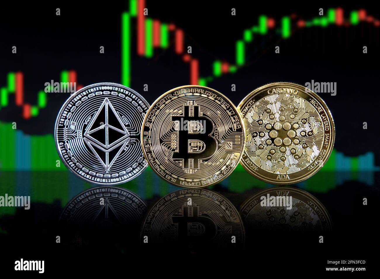 Ethereum (ether) bitcoin and cardano cryptocurrencies against candlestick chart Stock Photo