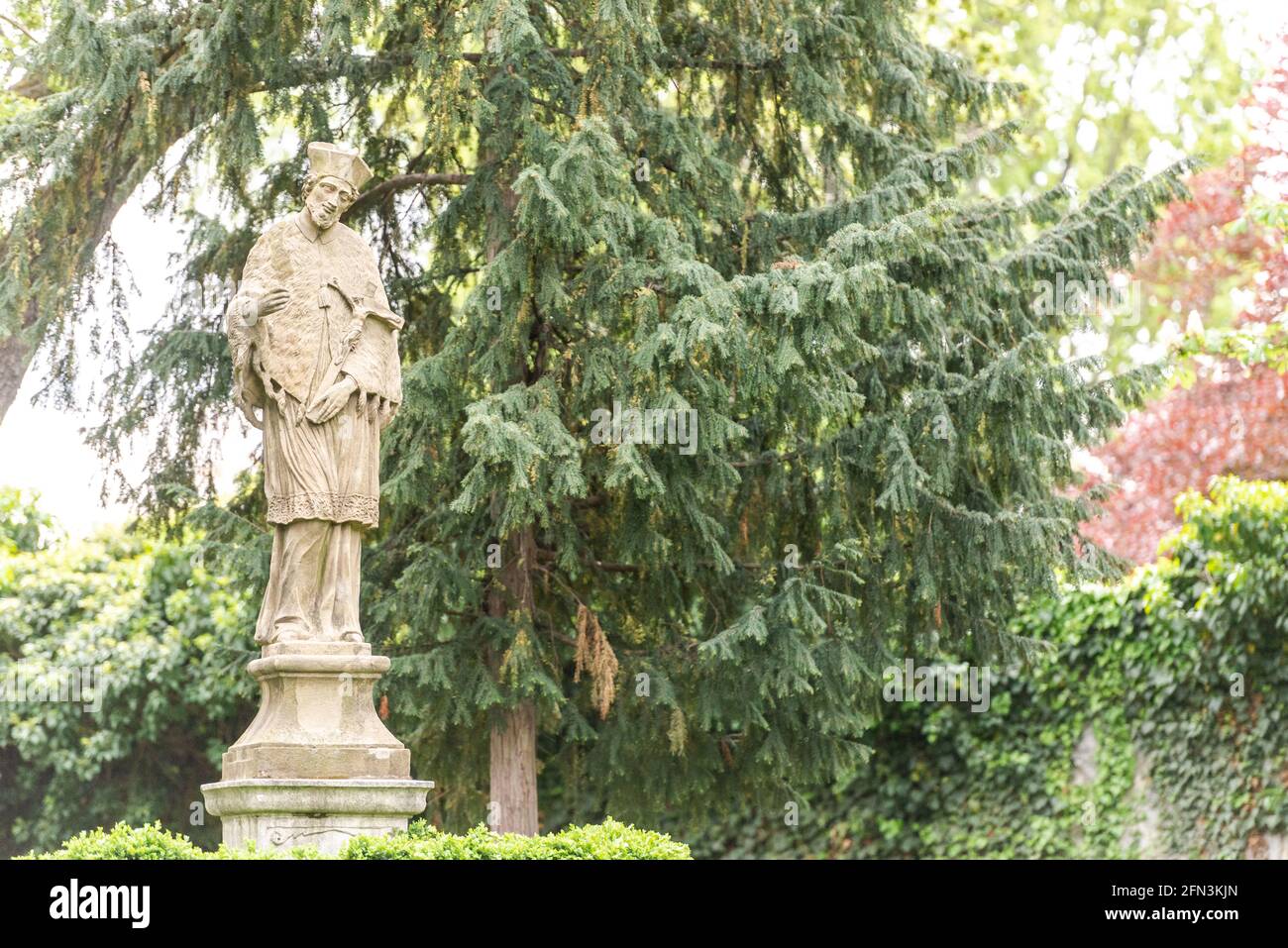 Monument in the garden of Brno Castle. Stone monument to a man on the background of spring trees. Stock Photo