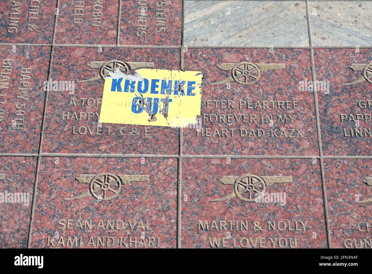 A 'Kroenke Out' sticker falls on top of the tribute area outside the Arsenal football ground as fans protest against the over the club's ownership Stock Photo