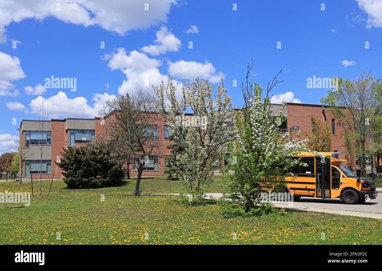 School building with school bus on a sunny spring day Stock Photo