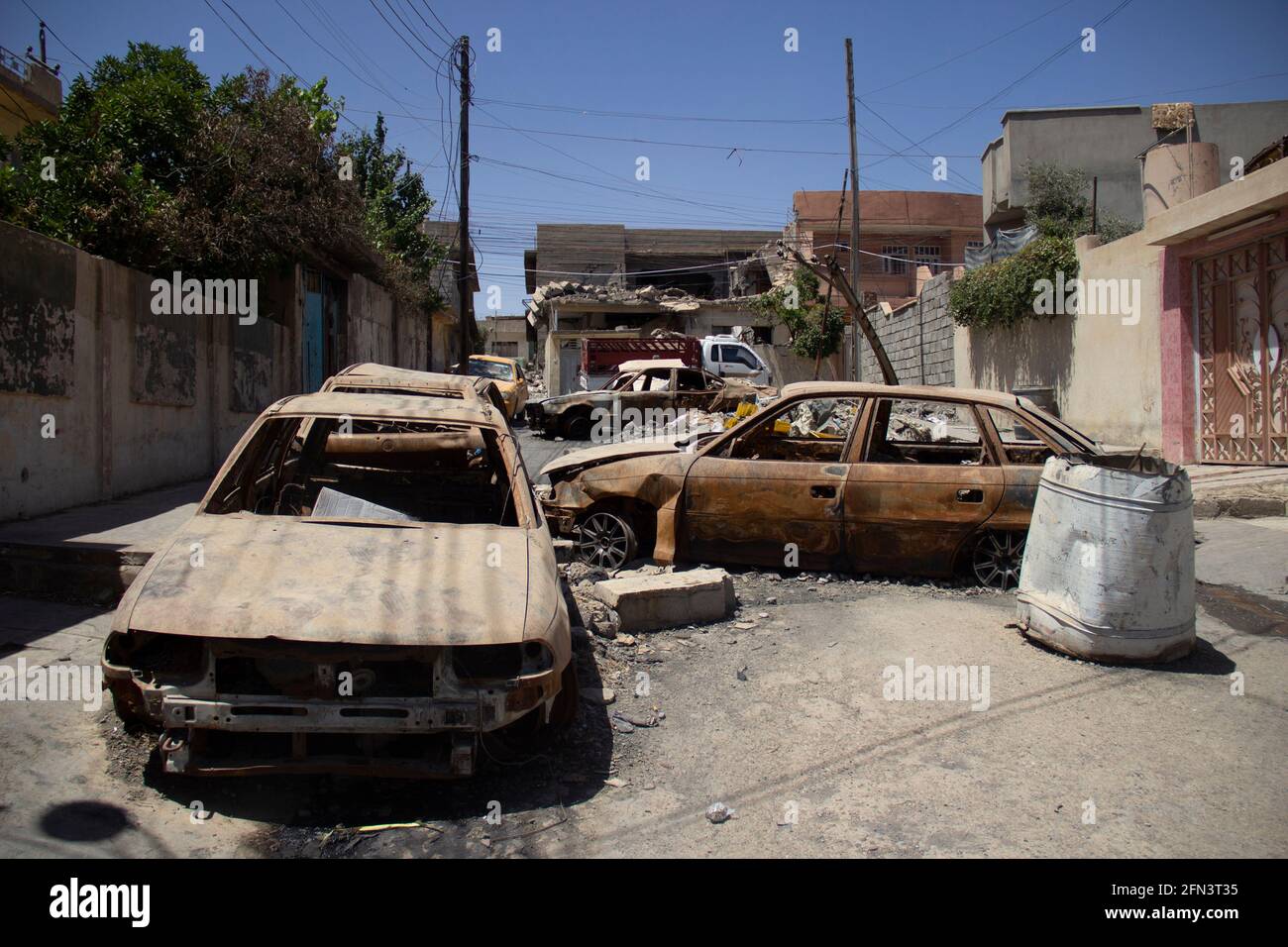 Destroyed vehicles block the road in West Mosul during the 2016-2017 Mosul Operation. Stock Photo