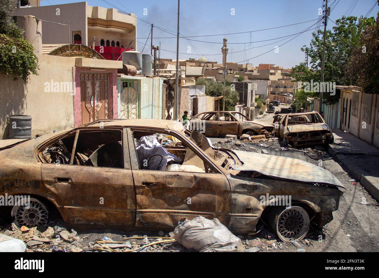 Destroyed vehicles block the road in West Mosul during the 2016-2017 Mosul Operation. Stock Photo