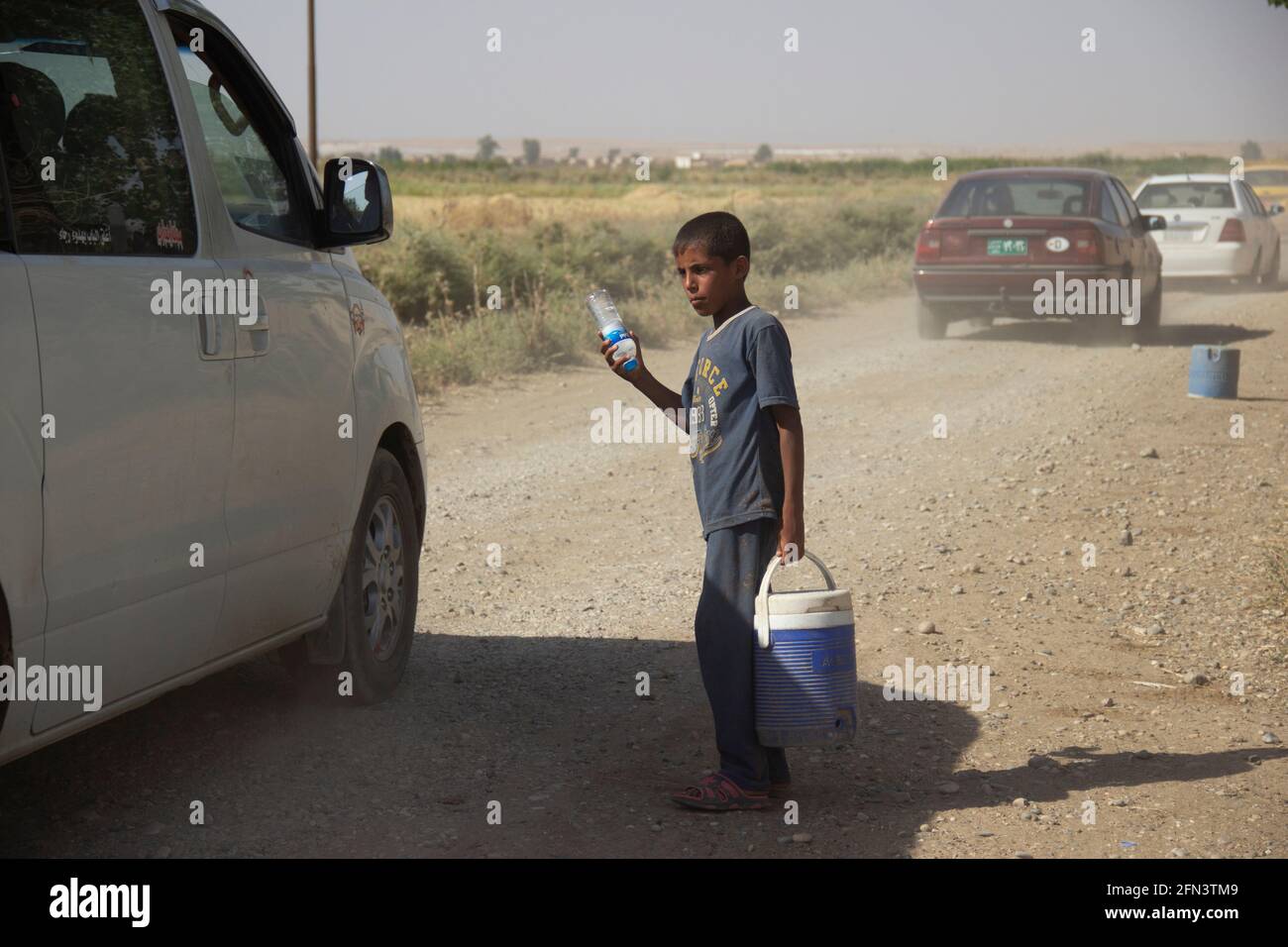 A boy vendor selling water on the outskirts of Iraq during the 2016-2017 Mosul Operation. Stock Photo
