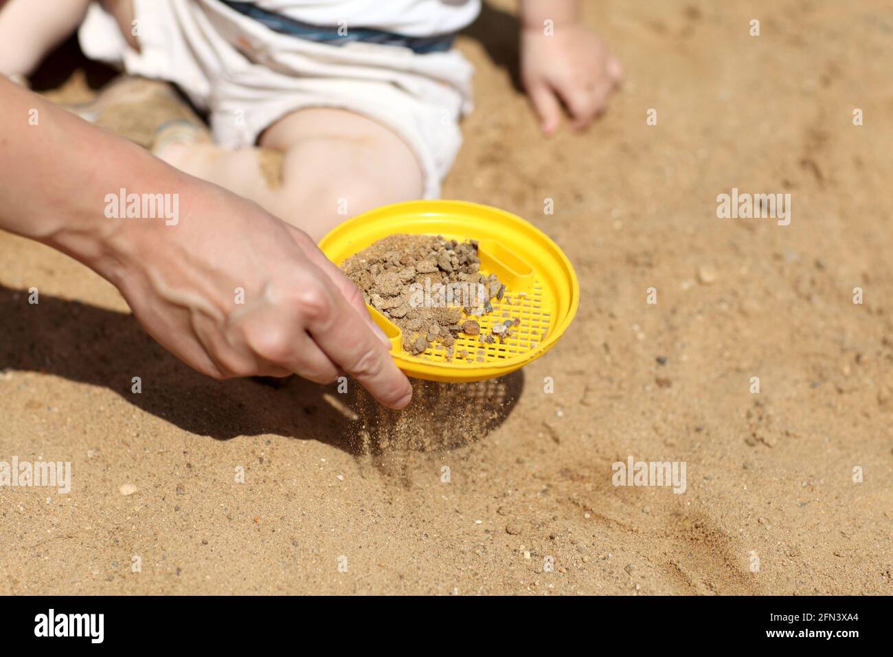Mother is sifting sand in sandbox in summer Stock Photo Alamy