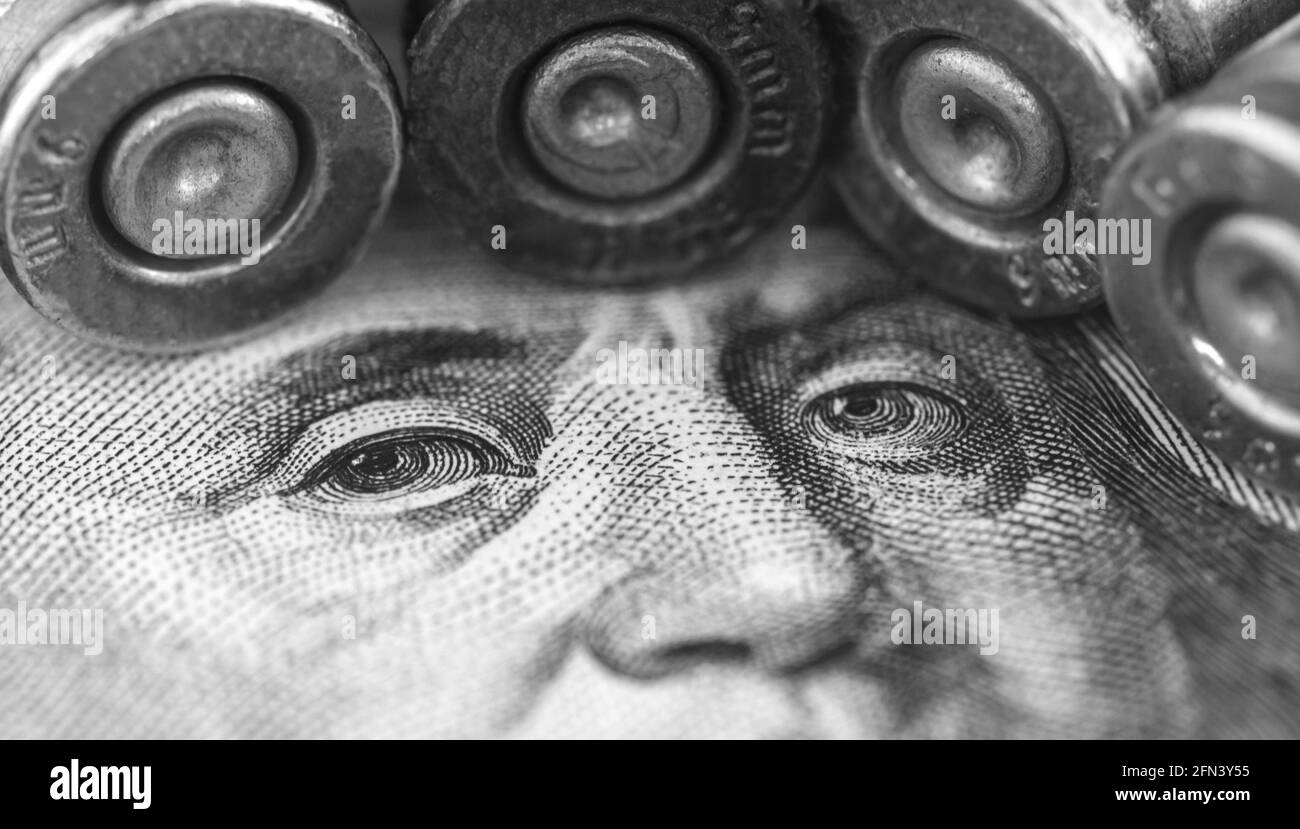 Criminal money laundering concept background, Benjamin Franklin face close-up with gun bullet Stock Photo