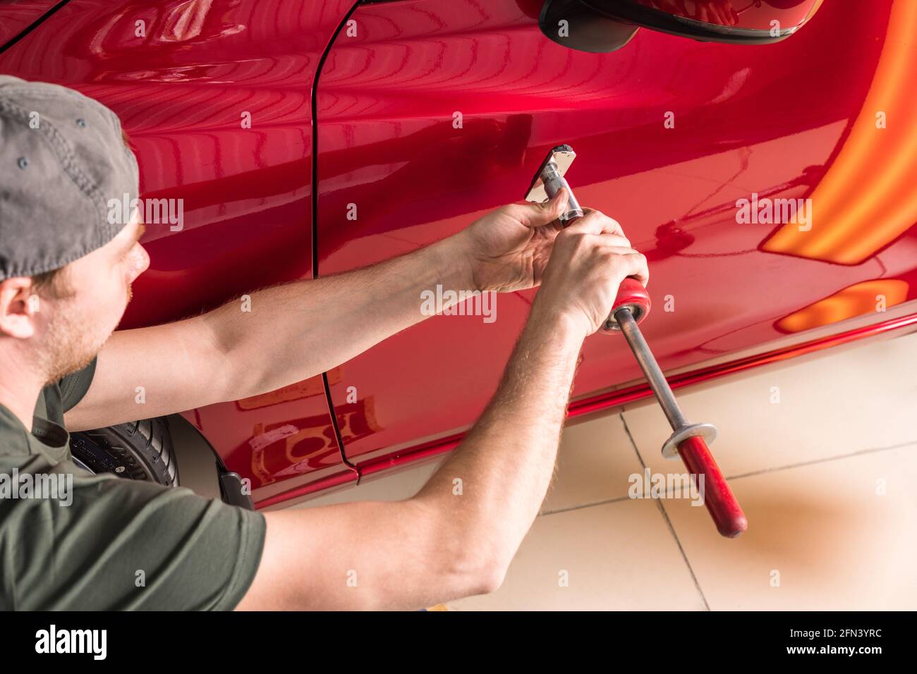 Repair of car dents. PDR technology. The master removes damage to the body. Stock Photo