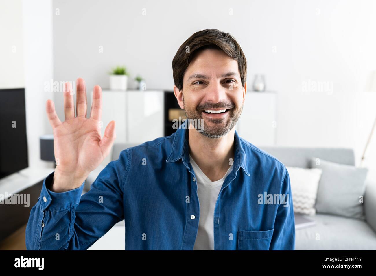Happy Man Portrait Waving To Webcam In Video Webinar Stock Photo