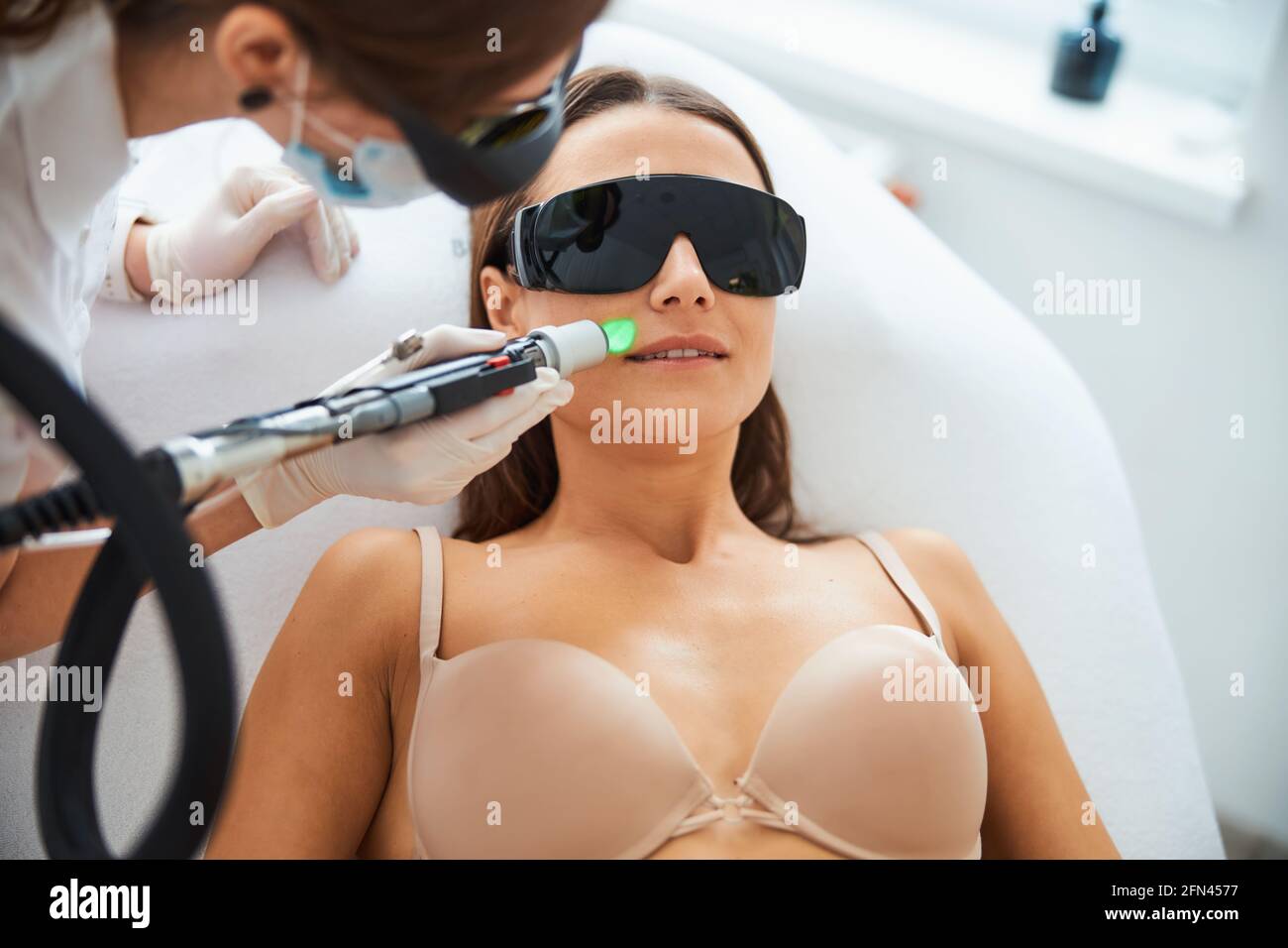 Beautician doing a laser epilation on the patient face Stock Photo