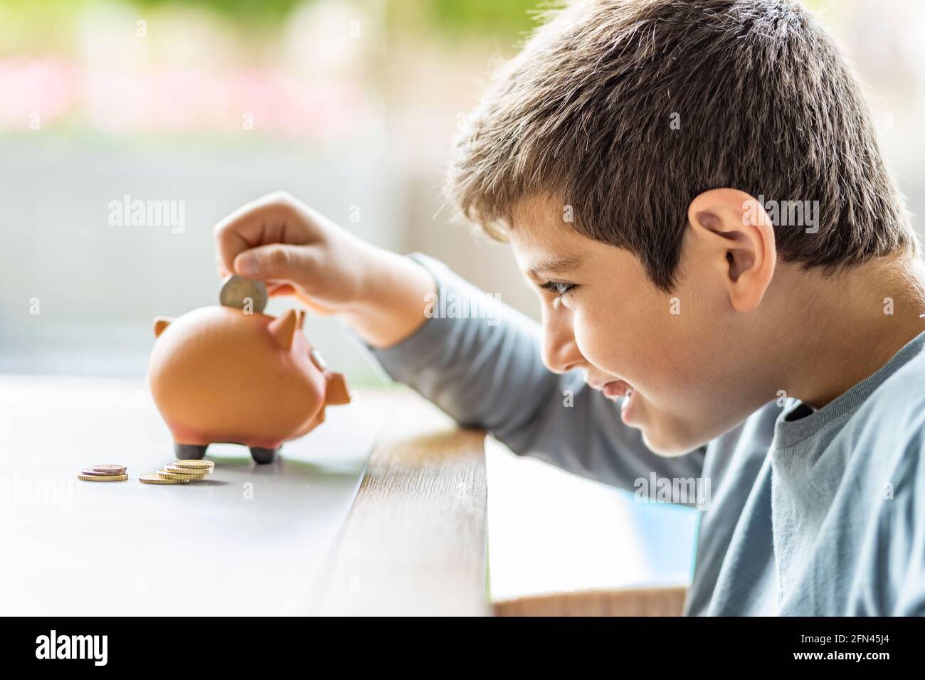 Little boy putting a coin in a piggy bank Stock Photo - Alamy