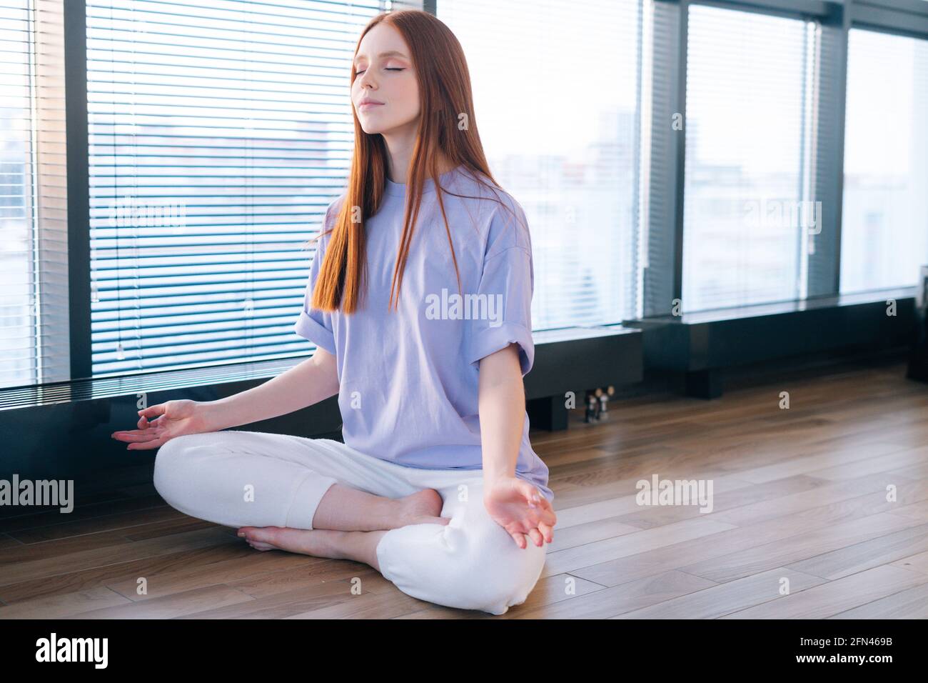 Close-up of happy peaceful young woman meditating sitting on floor in ...