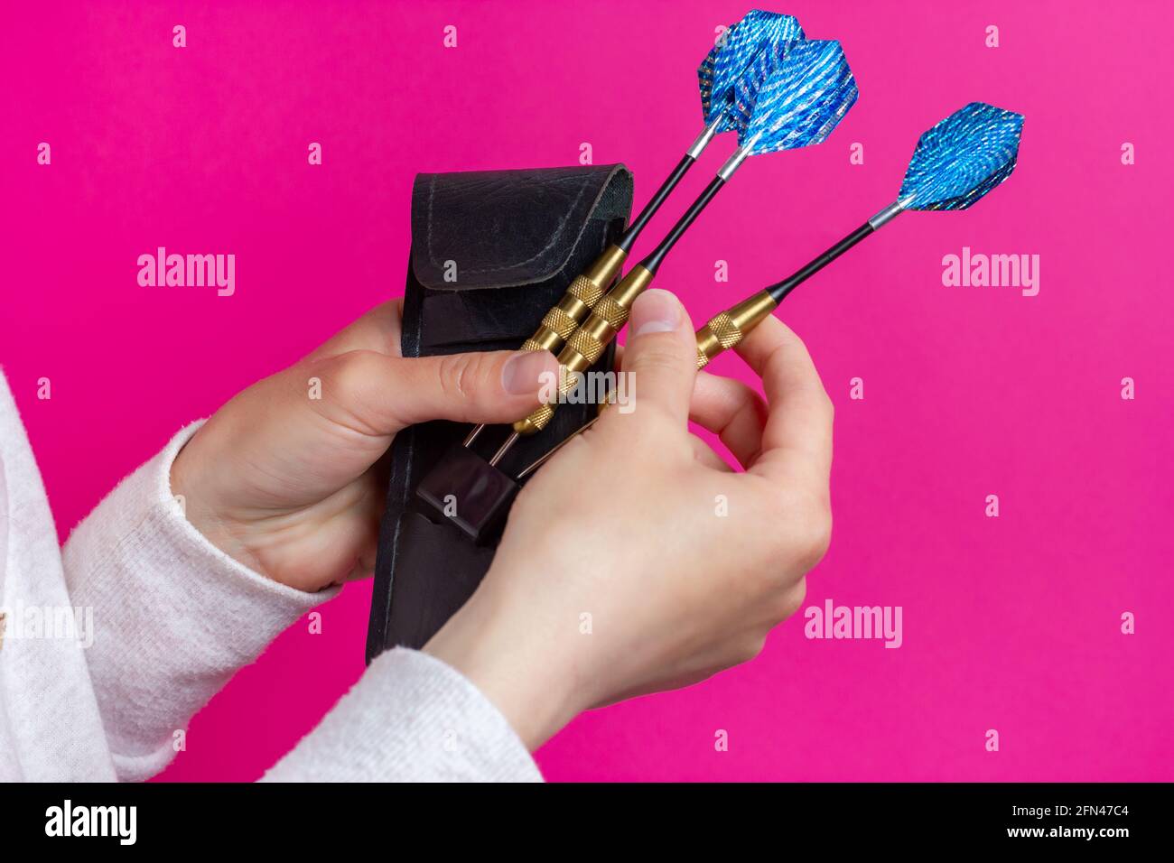 Choosing a dart. Three darts in the hands of the player. Stock Photo