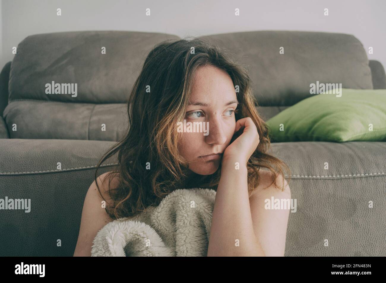 girl covered with a blanket and looking to the side pensively Stock Photo