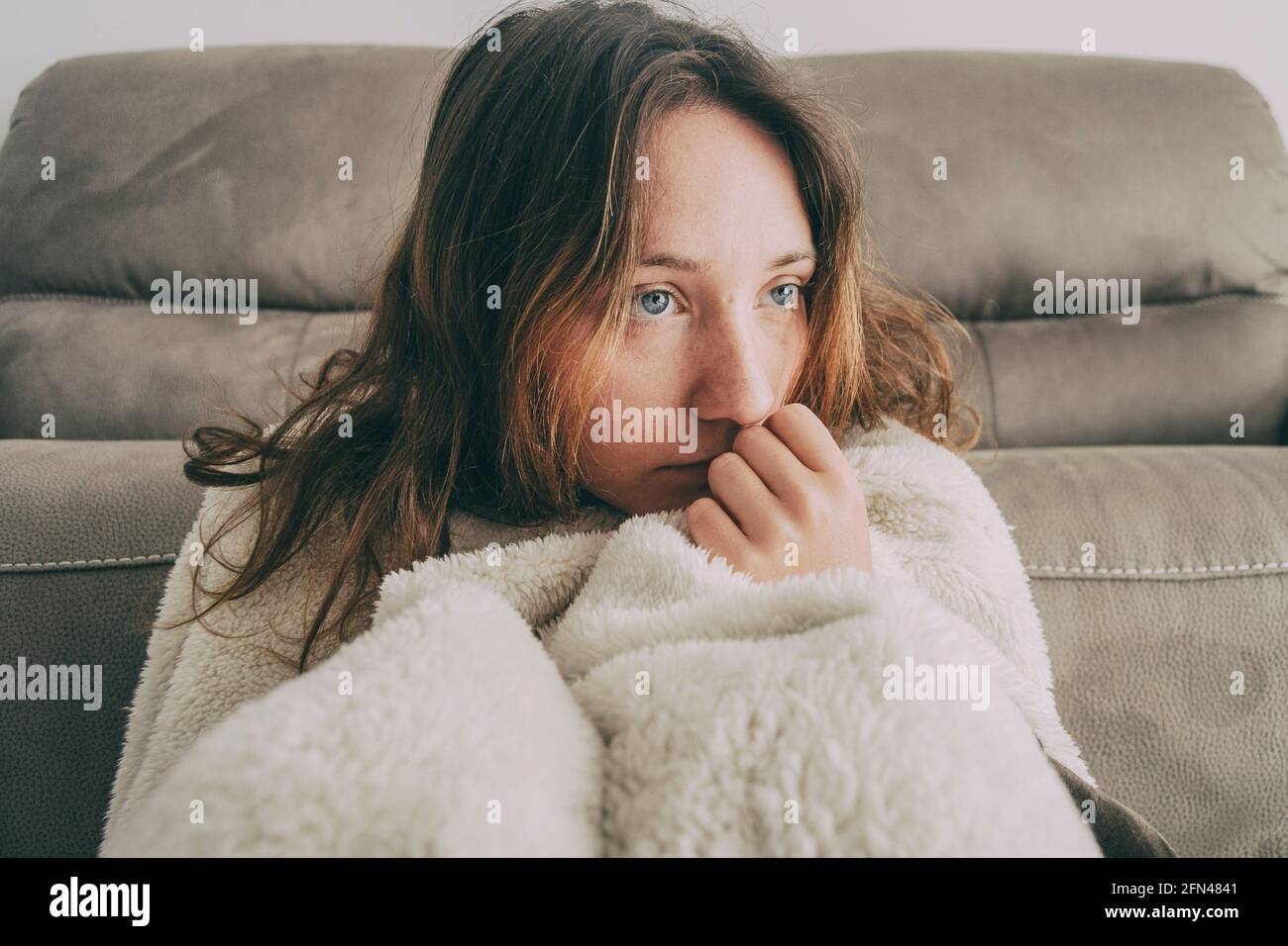 girl covered with a blanket and looking to the side pensively Stock Photo